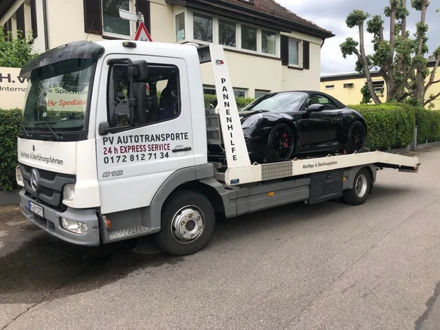 Schwarzes Porsche 911 Cabriolet auf einem Mercedes Atego Transportfahrzeug