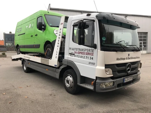 Grüner Renault Master auf einem Mercedes Atego Transportfahrzeug