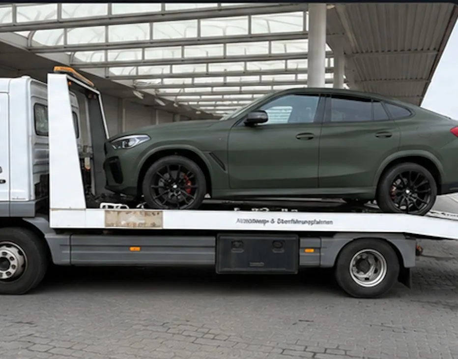 Grüner BMW X6 auf einem PV Transportfahrzeug
