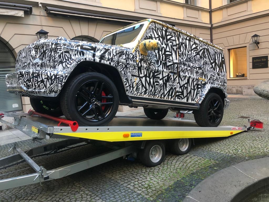 Getarntes Erprobungsfahrzeug seitlich auf einem Anhänger