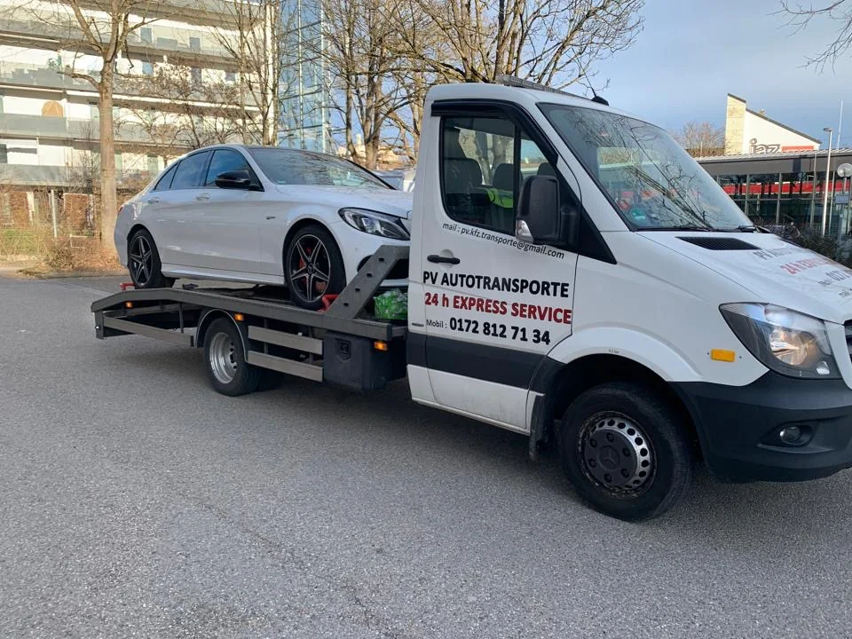 Weiße Mercedes-Limousine auf einem PV Transportfahrzeug